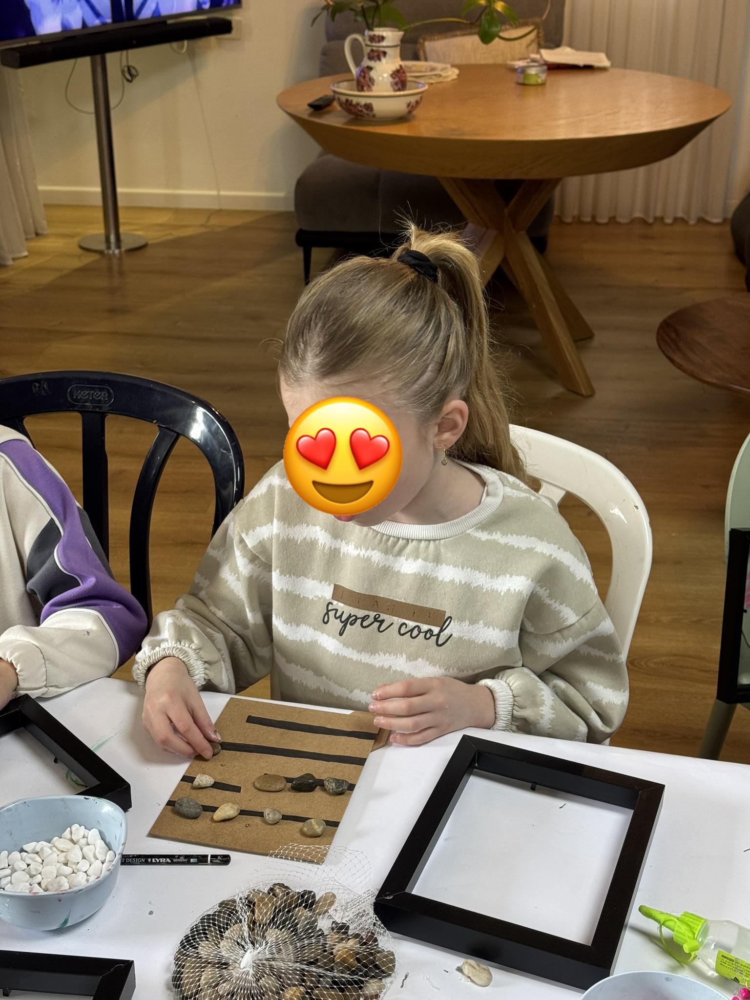 ילדה מסדרת אבנים על יצירה — קייטנת ArtyParty תל מונד